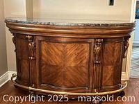 Front view of the wooden bar highlighting the marble top, wood grain, and carved details.
