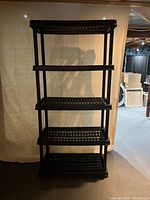 Front view of the black plastic shelving unit showing all five shelves and overall frame.