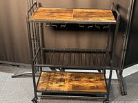 Front view of the portable wine rack showing wood top shelf with hanging wine glass holders, metal bottle racks, and wood bottom shelf.