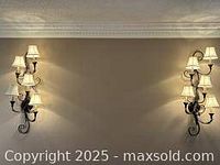 Both black wall sconces mounted on wall, showing overall look and scale with five lit lights each and cream pleated lamp shades.