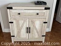 Front view of white and black metal console showing drawer and cupboard doors with black metal handles and accents.