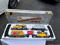 Caterpillar Express battery-operated train set displayed in packaging with partial contents visible including train cars and tracks