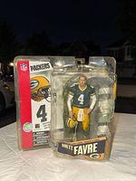 Front view of Brett Favre figure in damaged blister packaging, showing figure in Packers uniform with number 4 and helmet, McFarlane Toys branding visible