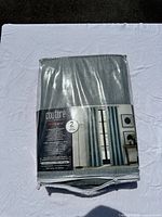Front view of the Couture by Commonwealth ThermaPlus gray curtain package showing brand name, product features, and photo of curtains hanging on a rod