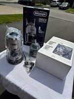 Overview of grinder wrapped in protective plastic, original box and styrofoam insert on table