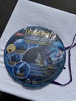 Photo of the Dream Tents Winter Wonderland bed tent flat and packaged in circular folded form, showing front product labeling and features.