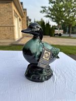 Front and side view of ceramic bird sculpture with attached Blue Mountain Collection hang tags.