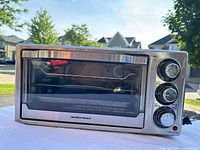 Front view of stainless steel Hamilton Beach electric oven showing glass door and control knobs.