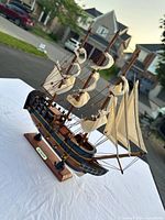 Side angle showing the full profile of the HMS Endeavour wooden model ship with sails and display stand.