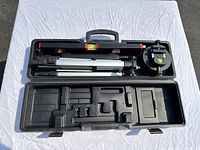 Open black case containing the spirit level, tripod, and compartments for accessories.