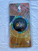 Photo showing front view of sealed package featuring a trading pin for an NBA team (Toronto Raptors) from the 1995 limited edition collection, with holographic text highlighting 29 teams included.