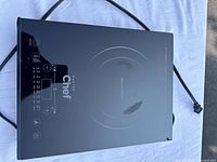 Top view of the Master Chef induction cooktop showing black glass surface with visible scratches and touch control panel.