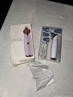 Multifunctional cleaning device, box, instruction manual, one charging cable, and four interchangeable heads arranged on a surface.