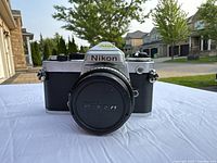 Front view of Nikon EM with lens cap on, showing Nikon logo on prism housing.