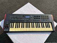Top view of Novation Impulse 49 keyboard showing keys, faders, knobs, pads, and display.