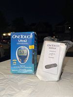 Front image of OneTouch Ultra2 box with glucose meter display showing 5.3 result, and manual for OneTouch Delica lancing device
