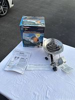 ProTemp propane heater unit, original box, user manual and printed instructions laid out on a white cloth on pavement.