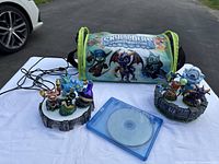 Skylanders Spyro's Adventure game set items including game disc in case, three figurines on the portal base, and carrying bag