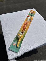 Full view of factory-sealed yellow Zebco Snoopy fishing rod and reel in original packaging, displayed on white cloth.