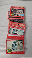Photo of multiple Star Wars trading cards laid out, showing the card front with the red border and scenes from the movie including R2-D2.