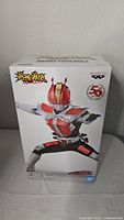 Front view of the boxed Banpresto Masked Rider Den-O figure showing character in battle pose with red armor and 50th anniversary logo.