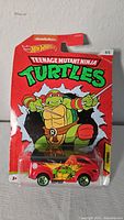 Front view of new Hot Wheels Teenage Mutant Ninja Turtles Vanster die-cast car in original packaging with Raphael image.