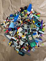 Pile of assorted LEGO pieces including bricks, various colors and shapes, some transparent and printed elements visible.