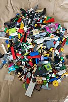 Pile of assorted LEGO pieces with varied colors and types spread on brown paper.