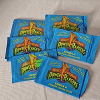 Six sealed trading card packs of Mighty Morphin Power Rangers Series 2 laid out on a surface, showing front packaging.