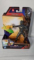Front view of new Marvel Studios Spider-Man black stealth suit figure in original packaging, showing figure holding yellow web accessory.