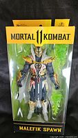 Photo showing the front of the sealed box with the Malefik Spawn figure visible inside, including green energy accessory.