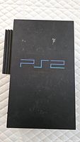 Top view of the Sony PlayStation 2 console showing the PS2 logo and some surface wear.