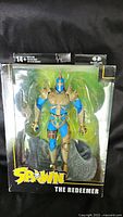 Full front view of The Redeemer figure in packaging showing blue and gold armor details and Spawn logo