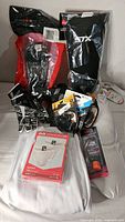 Wide view of lot contents including gloves, arm guards, grooming spray, athletic supporter, and protective gear.