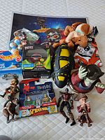 Top view showing the assortment of toys including Marvel action figures, Hot Wheels car, Dorbz collectible, and Star Wars plush and figures placed on a blue starry background mat