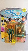 Front view of sealed Star Trek The Next Generation Beverly Crusher action figure with accessories in blister pack and branded backing card.