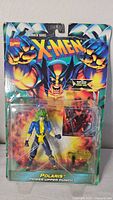 Front view of vintage X-Men Polaris action figure in original package with colorful Wolverine artwork and included trading card visible.