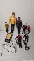 Full view of multiple Star Trek figures of varying sizes and accessories on a flat surface.