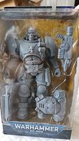 Front clear display of the gray plastic Space Marine figure with extra helmet and rifle accessory inside original packaging.