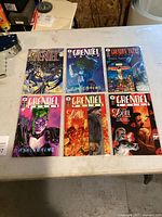 Seven comic books on a table, featuring various covers from the Grendel series and related titles by Dark Horse Comics.