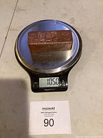 Copper bar weighing 1050 grams on digital scale with maxsold lot tag below.