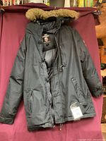 Front view of black Geographical Norway Legend Collection men's winter jacket with fur-lined hood, size tag visible.