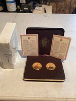 Two gold plated official medals in presentation case with two certificates of authenticity.