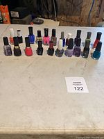 Full array of 17 assorted nail polish bottles arranged in a single row showing various colors and brands.