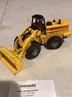 Yellow Majorette metal loader toy with front bucket facing sideways showing loader arm articulation and tire details.