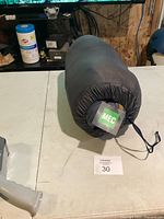 Sleeping bag rolled in black mesh storage sack with MEC tag visible