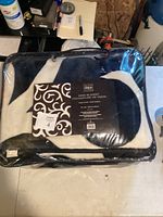 Packaged black and white mink blanket in clear carry bag showing the Maison Style At Home label