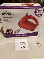 Front view of Rival hand mixer box showing product image, brand, and one-year warranty circle.