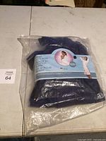 New navy blue fleece robe in original plastic packaging on a white table.