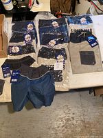 Photo showing multiple pairs of kids swim shorts on a table, some in packaging labeled Surfer Star, in various colors and sizes.